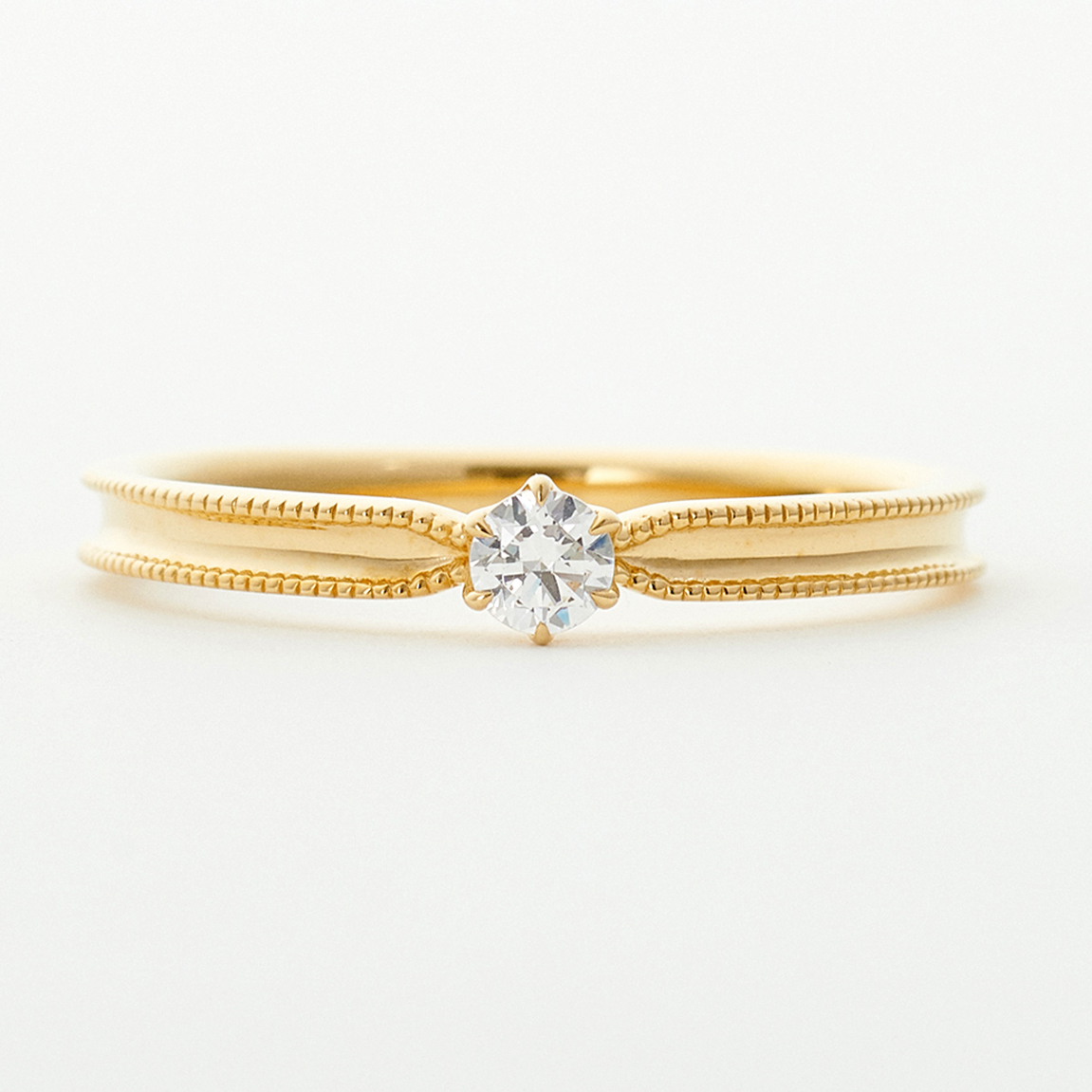 婚約指輪“シンプル“ | 矢の先端のように先細の形のリングアームが、親しみやすいサイズのダイヤモンドを支えるフォルム。中心をくぼませたリングの両サイドには、ミルグレインのアクセントを。いつでもさりげなく身につけられるデザイン。